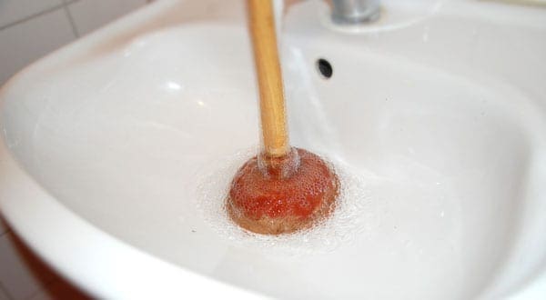 5 using pluner on clogged drain - DIY vs. Tradesman Hire: A few easy home repairs every man should master